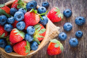 blueberries and strawberries in a bowl on a table.