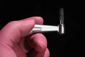 an implant being held up by a doctor with a tool for placement